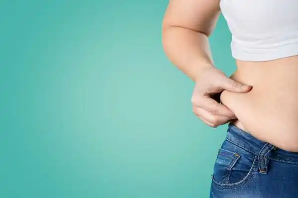 Image of woman pinching her love handles to show weight gain Lewisham
